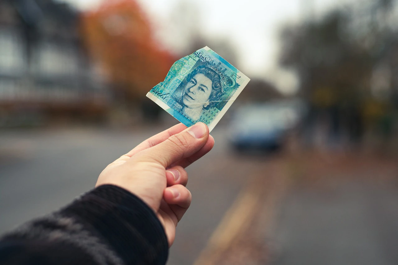 hand holding up torn british bank note