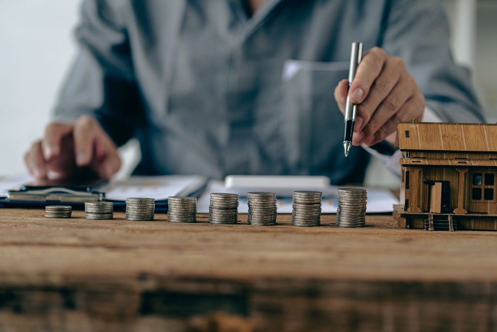 Close-up shot of silver coin drop and house model