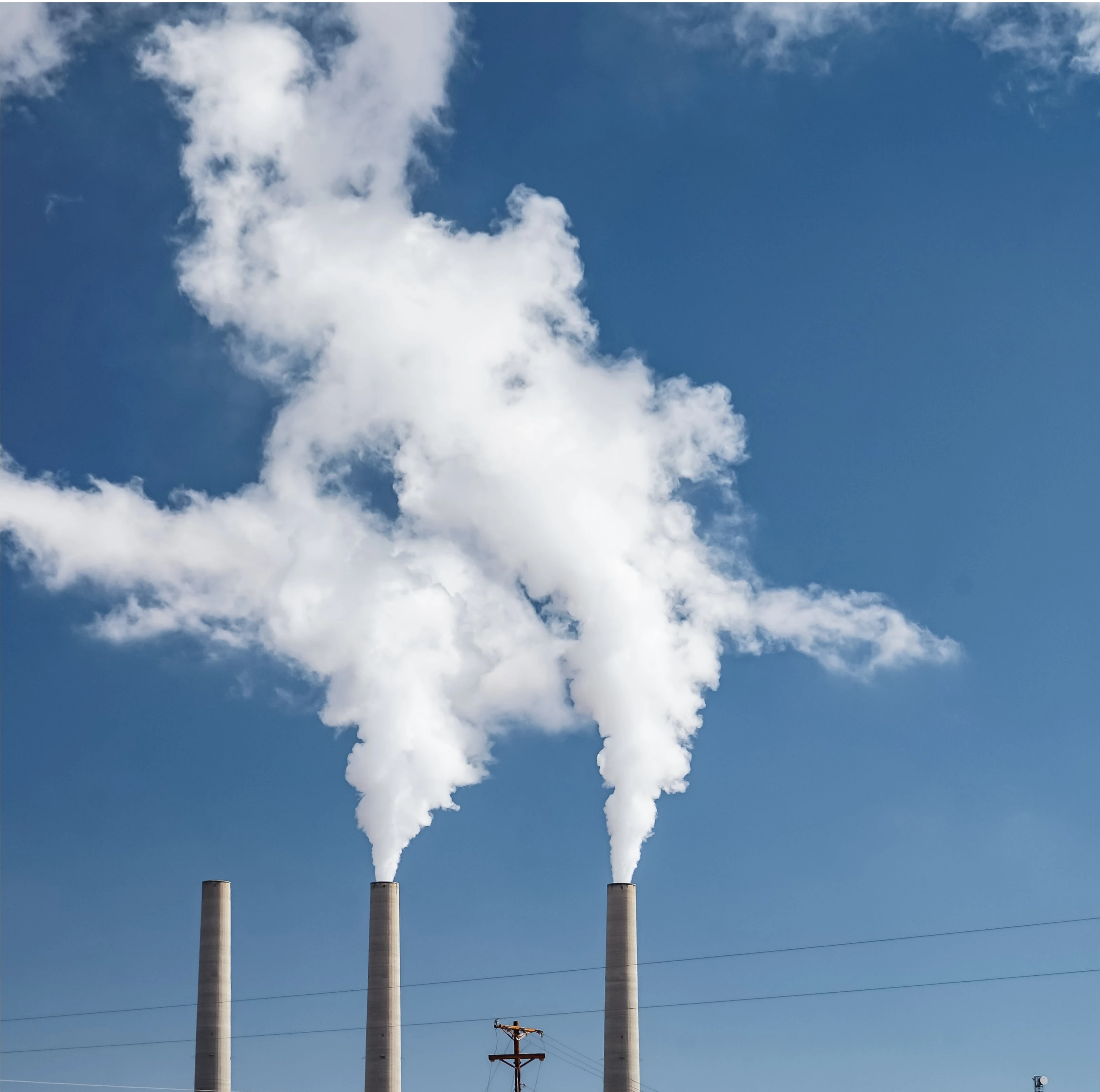 Smoke stacks of an industrial building emitting white smoke