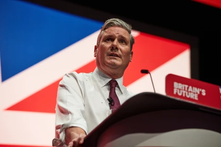 A photo of Keir Starmer standing behind a podium with the Union Jack behind him