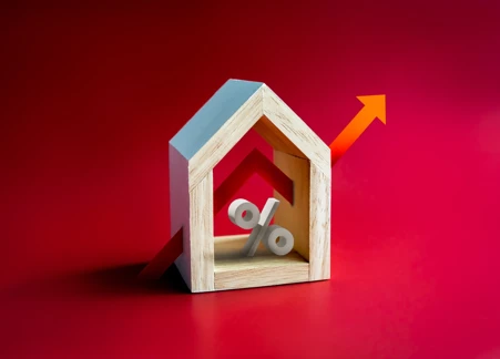 wooden block house with arrow and percentage sign cutting through middle on red background