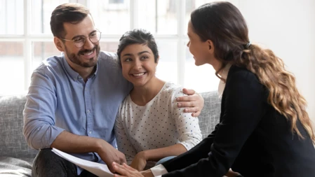 Smiling young man in eyeglasses hugging wife, listening to financial expert