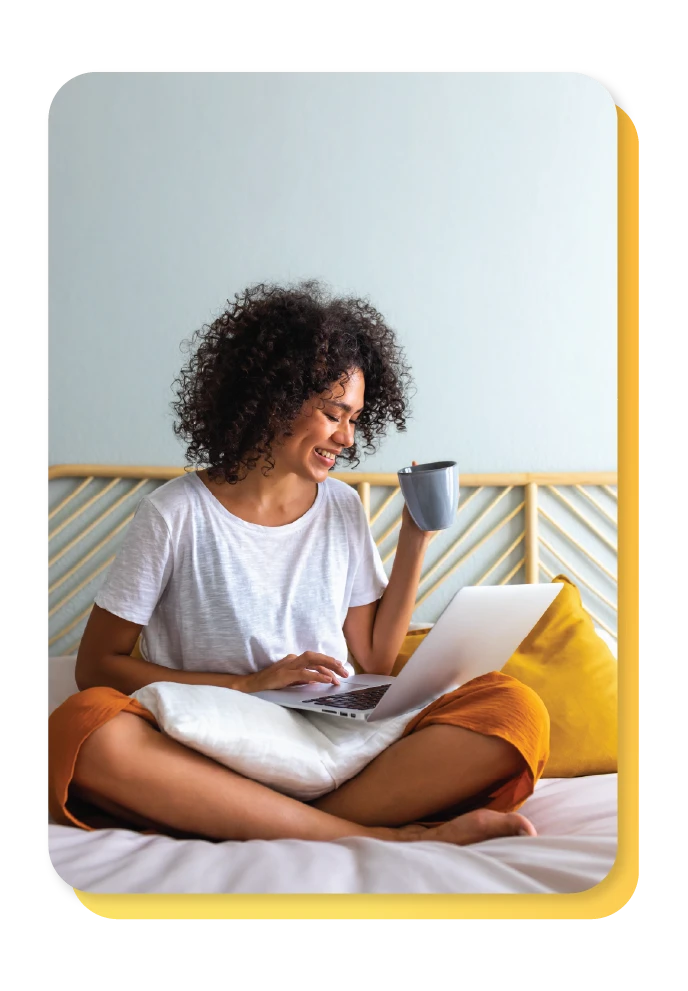 Women reading her laptop with a cup of tea learning about how to improve credit score.