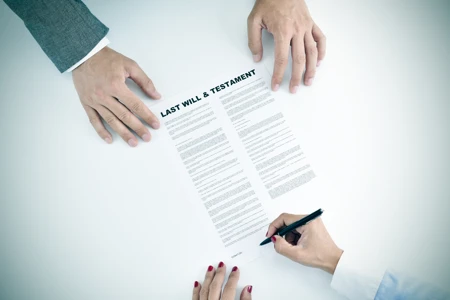 high-angle shot of a young woman signing a last will and testament document in front of a young man