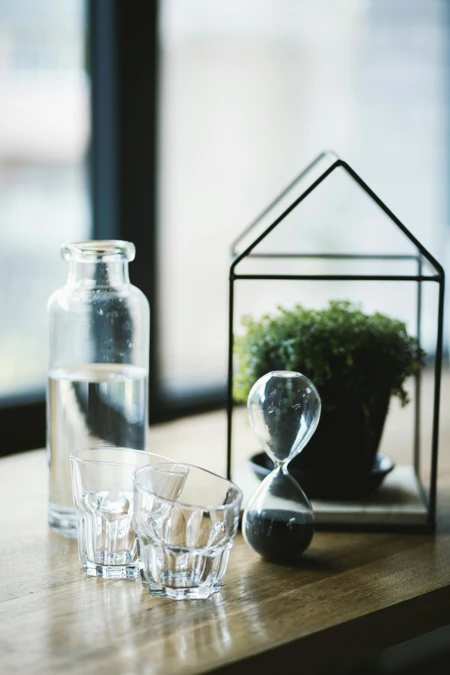 hourglass house vase with plant and water glasses
